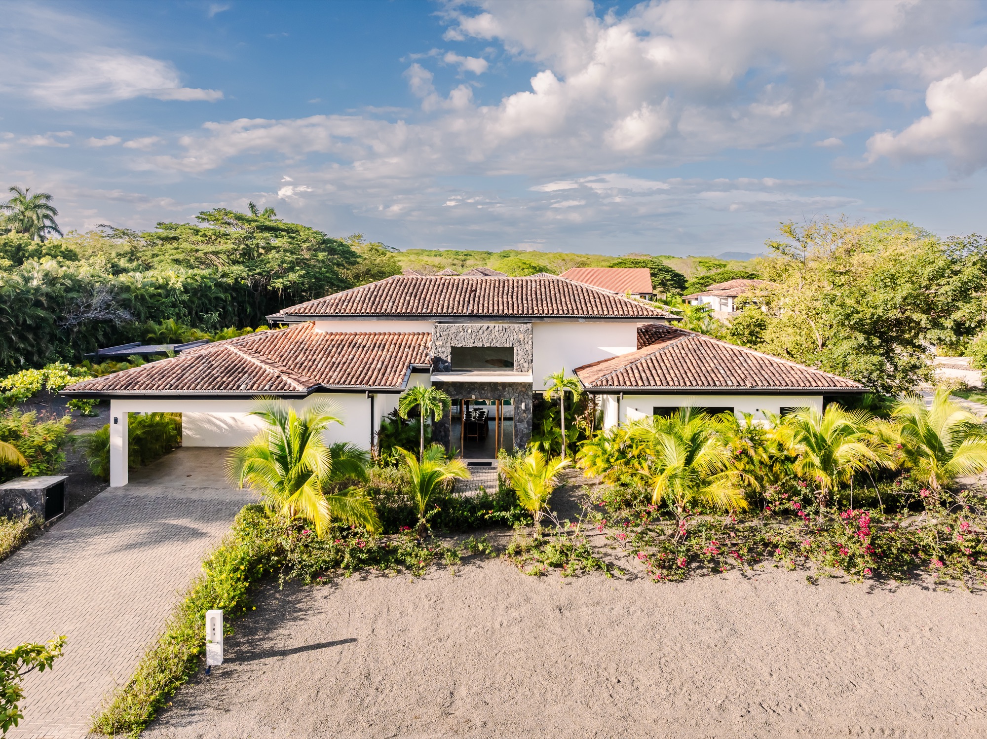 The front of Villa Reserva 101 in golden-hour light, palms and bougainvillea in the garden